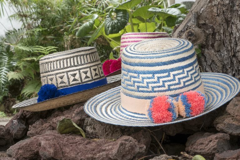 Sombreros wuayuu de distintos colores sobre unas piedras volcánicas